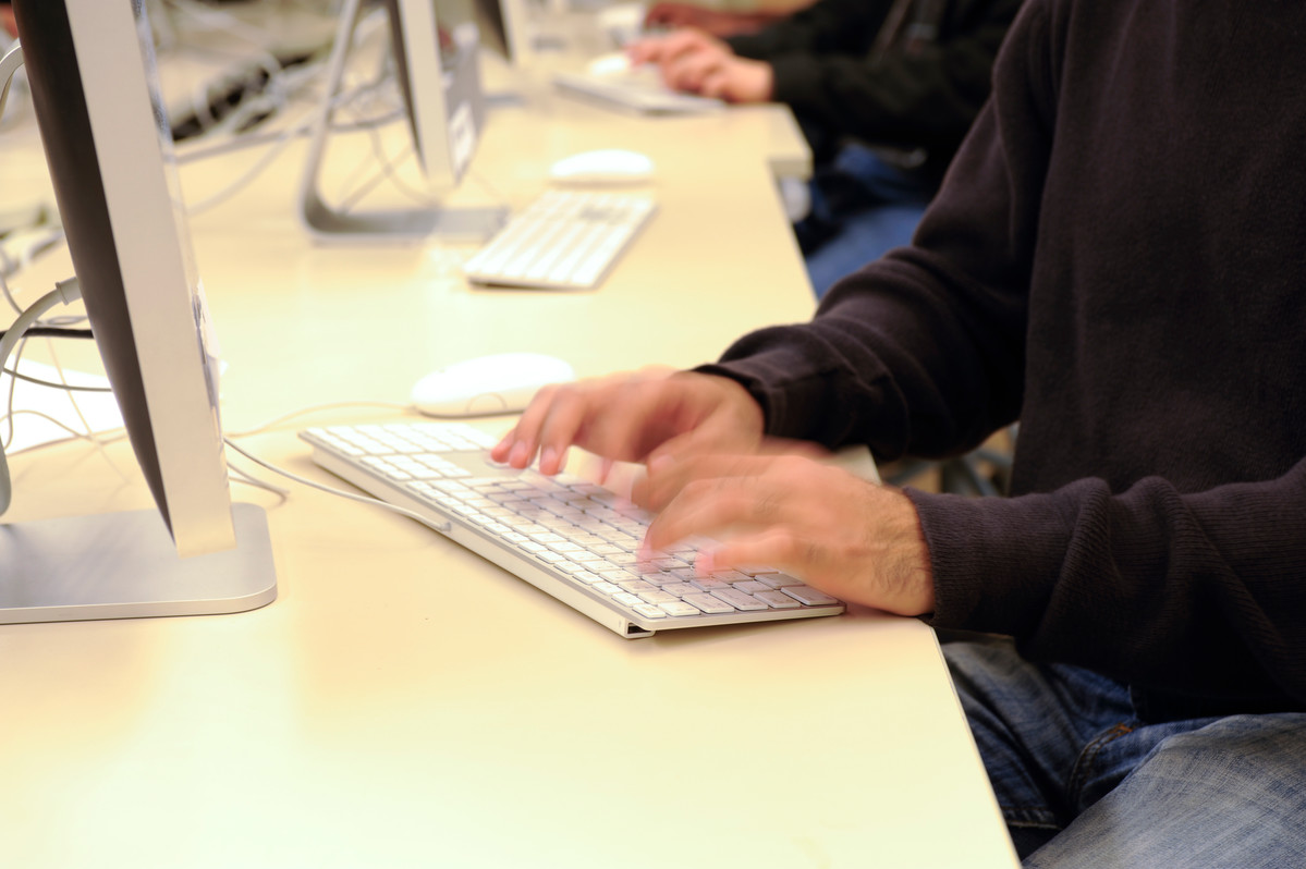 student typing on apple computer