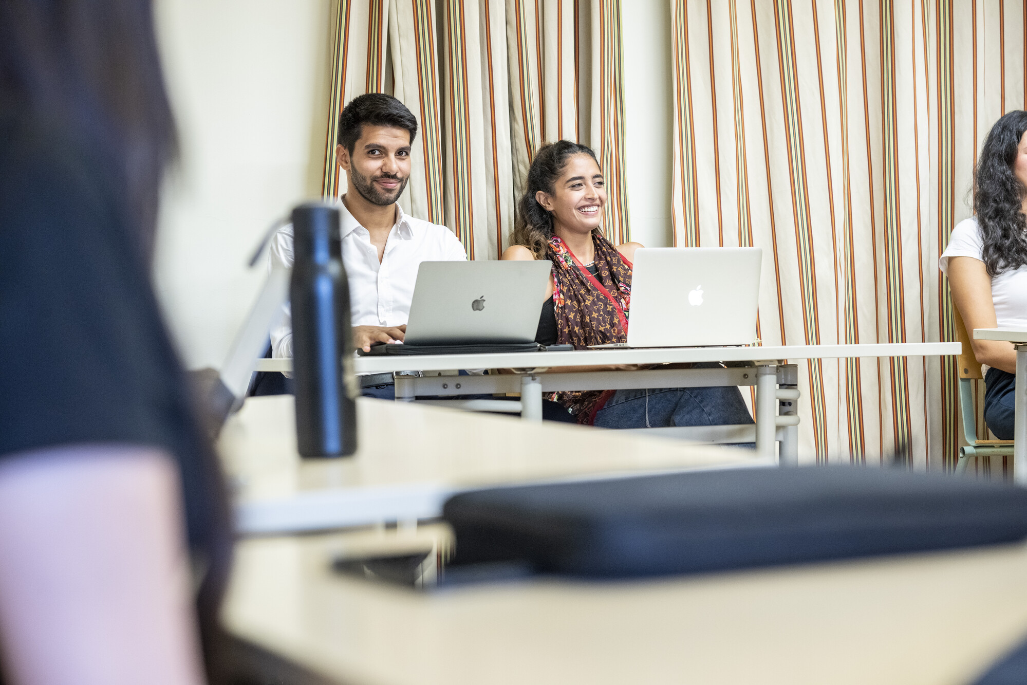 students in class taking notes on laptops