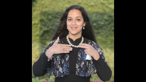 A woman is smiling, she is wearing jewelry
