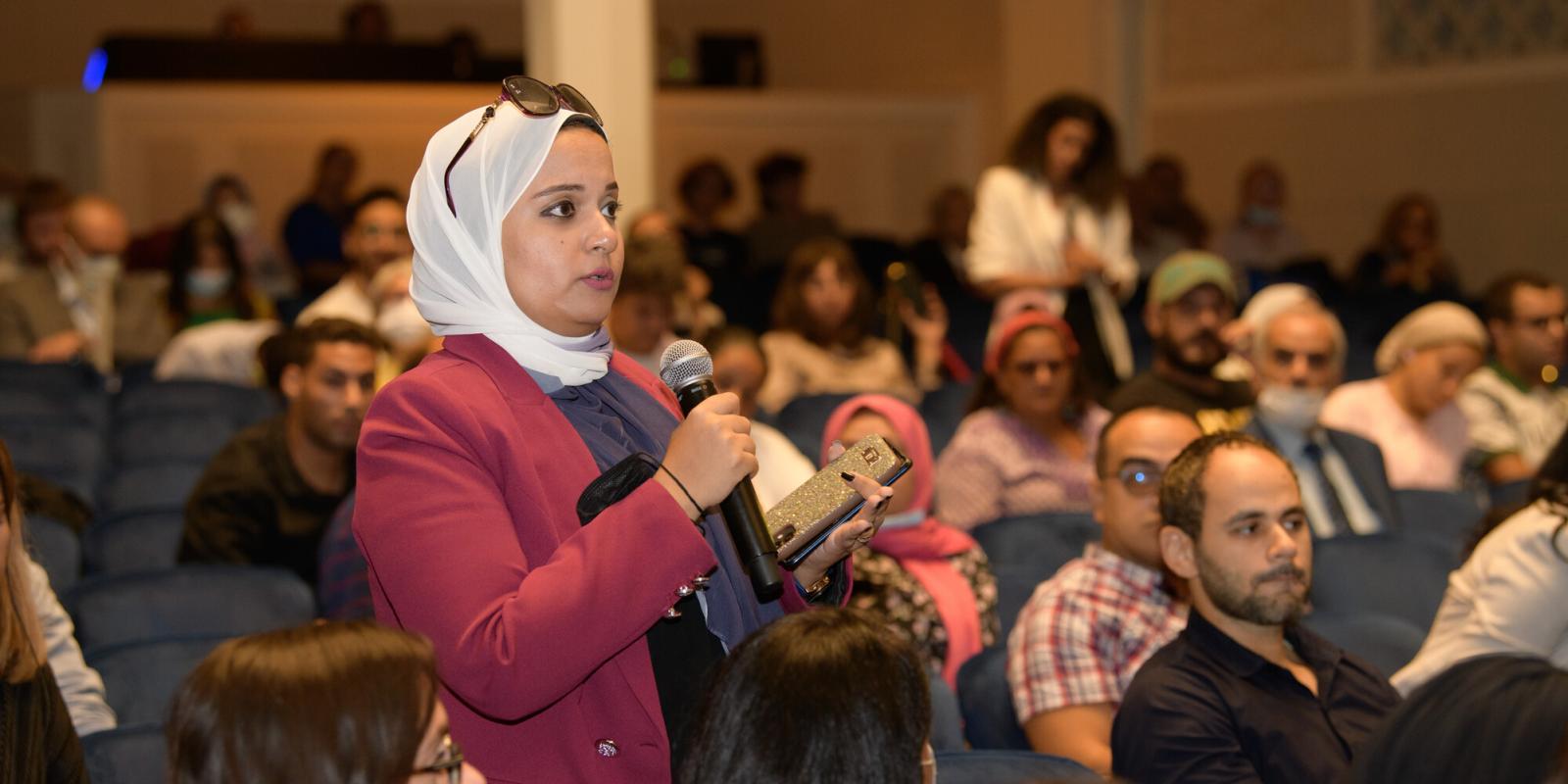 female guest attendee asking questions on mic in the hall