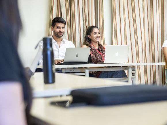 students in class taking notes on laptops